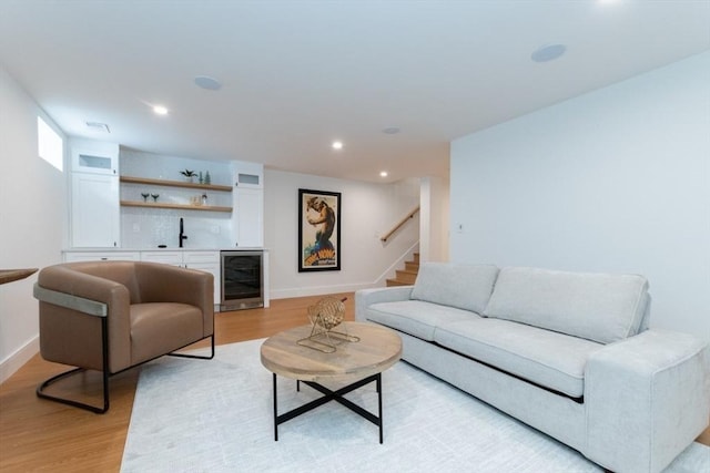 living room featuring light hardwood / wood-style floors, bar area, and wine cooler