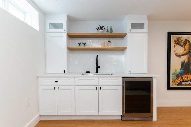 bar featuring sink, white cabinetry, and beverage cooler