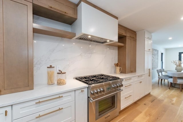 kitchen featuring stainless steel stove, light wood-type flooring, white cabinets, and decorative backsplash