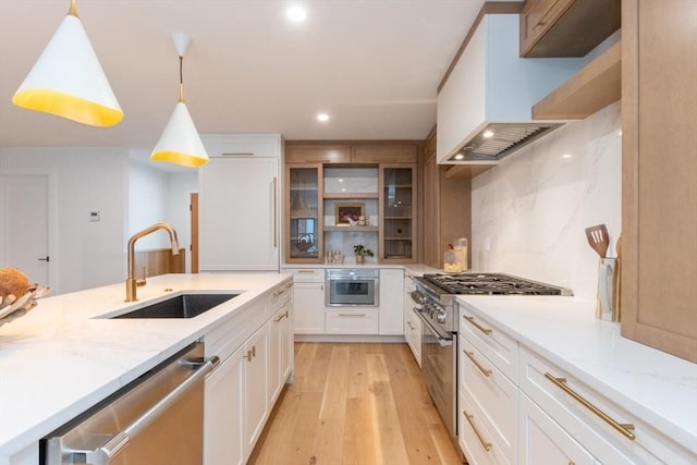 kitchen featuring hanging light fixtures, sink, premium range hood, white cabinetry, and stainless steel appliances