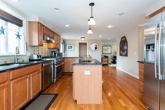 kitchen featuring sink, dark stone countertops, a kitchen island, pendant lighting, and stainless steel appliances