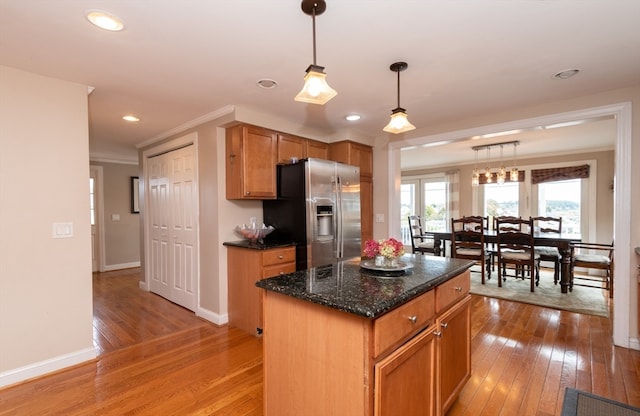 kitchen featuring pendant lighting, stainless steel fridge, light hardwood / wood-style flooring, and a kitchen island