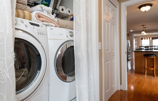 clothes washing area featuring wood-type flooring and washer and dryer