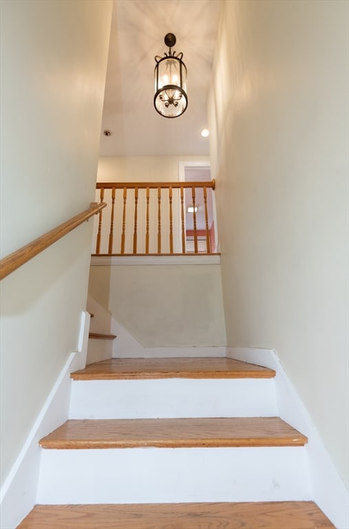 stairway featuring an inviting chandelier and hardwood / wood-style flooring