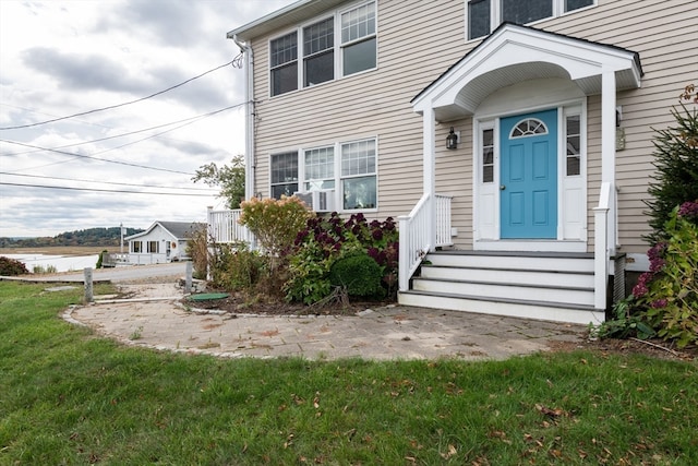 property entrance featuring a water view and a lawn