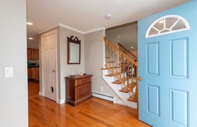 entryway with a baseboard radiator, ornamental molding, and light wood-type flooring