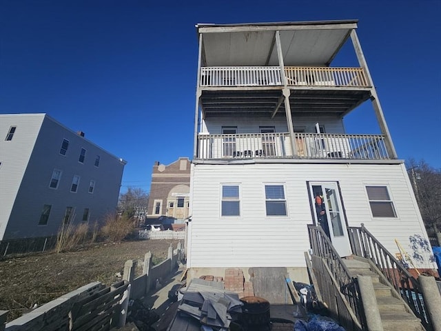 rear view of house with a balcony and fence