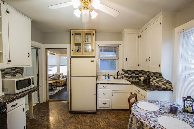 kitchen with white cabinets, decorative backsplash, white appliances, and sink