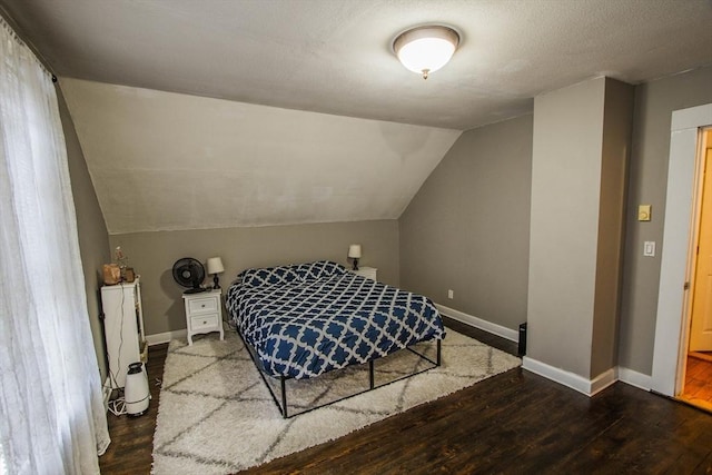 bedroom featuring a textured ceiling, dark hardwood / wood-style floors, and vaulted ceiling