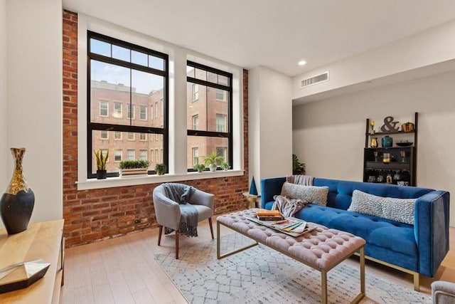 living room with hardwood / wood-style flooring and brick wall