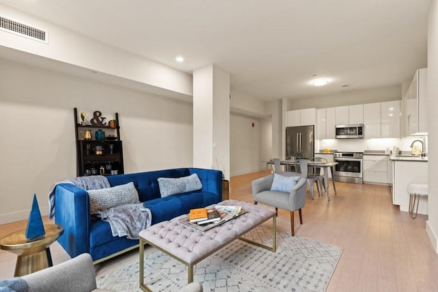 living room with light hardwood / wood-style flooring and sink