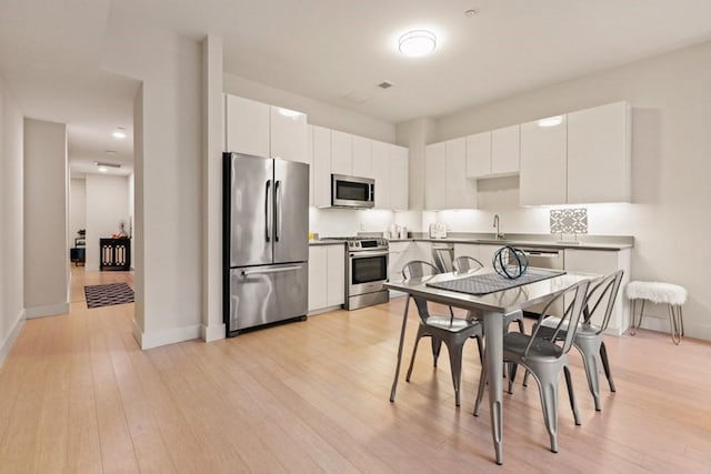 kitchen with sink, white cabinets, stainless steel appliances, and light wood-type flooring