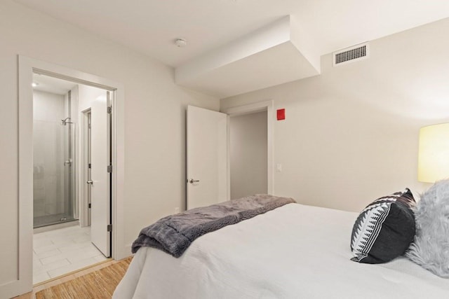 bedroom featuring connected bathroom and light hardwood / wood-style floors