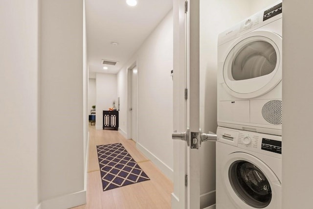 washroom with light hardwood / wood-style floors and stacked washer / dryer