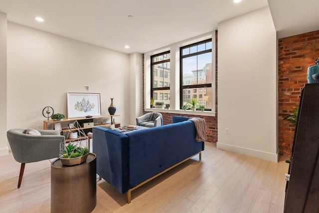 living room featuring brick wall and light hardwood / wood-style flooring