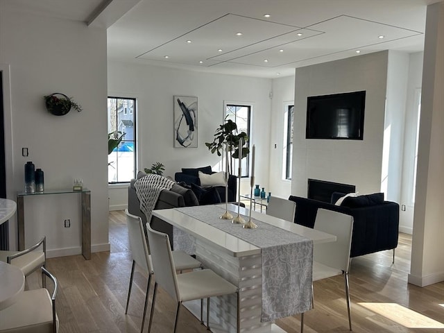 dining room featuring recessed lighting, a fireplace, light wood-type flooring, and baseboards