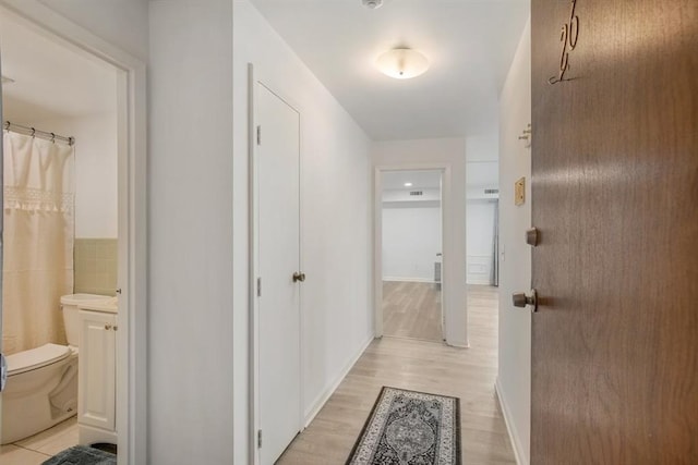 corridor featuring tile walls and light hardwood / wood-style flooring