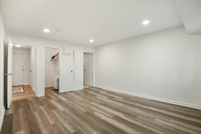 unfurnished bedroom featuring a walk in closet, wood-type flooring, and a closet