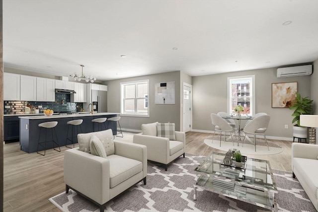living room with a chandelier, a healthy amount of sunlight, an AC wall unit, and baseboards