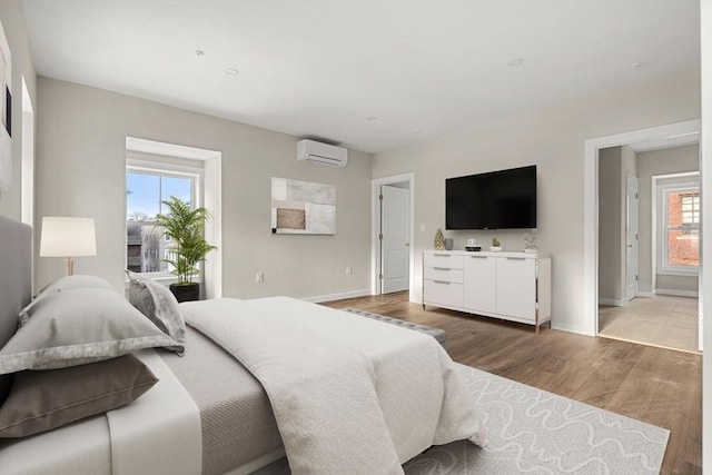 bedroom with light wood-type flooring, baseboards, and a wall unit AC