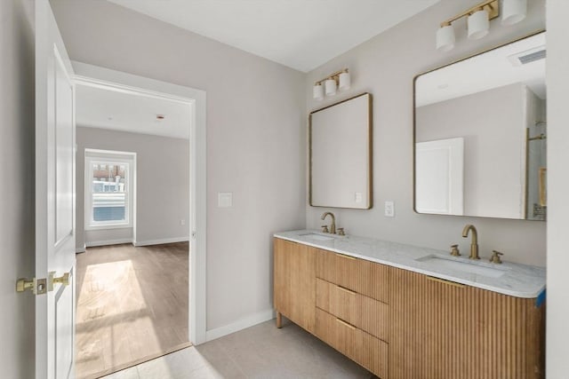 bathroom featuring visible vents, baseboards, a sink, and double vanity