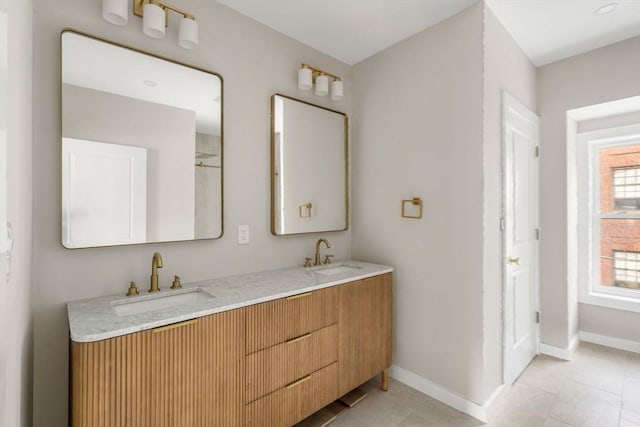 full bathroom with double vanity, tile patterned flooring, baseboards, and a sink