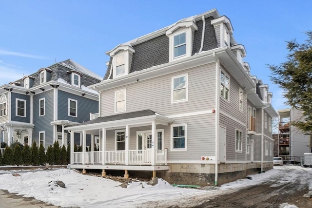 view of front of house featuring covered porch, a shingled roof, and mansard roof