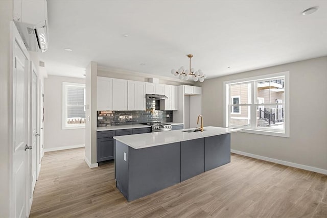 kitchen with light wood-style flooring, baseboards, a sink, and white cabinetry