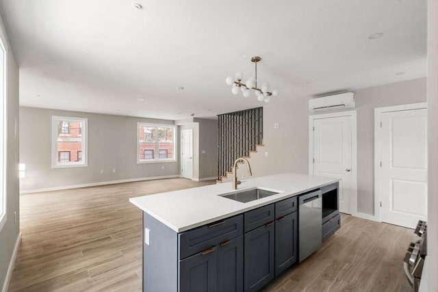 kitchen featuring an AC wall unit, baseboards, stainless steel appliances, and a sink