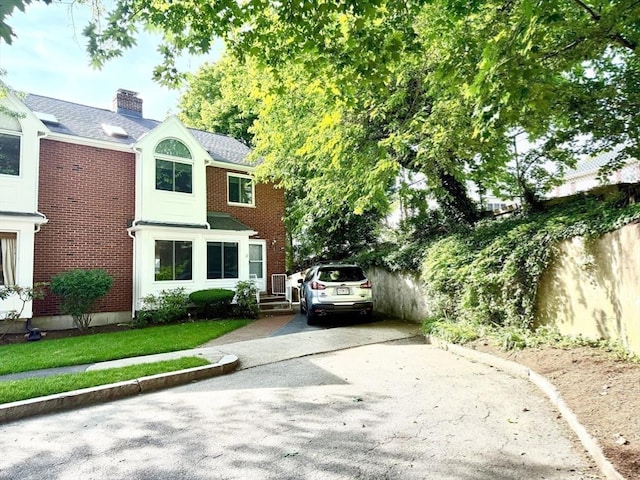 12 Cozy St Unit 12, Watertown, MA 02472 - view of front facade with brick siding, a chimney, concrete driveway, and roof with shingles