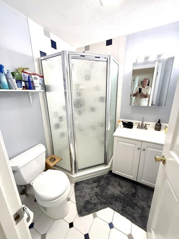 12 Cozy St Unit 12, Watertown, MA 02472 - bathroom with vanity, a textured ceiling, and a shower stall