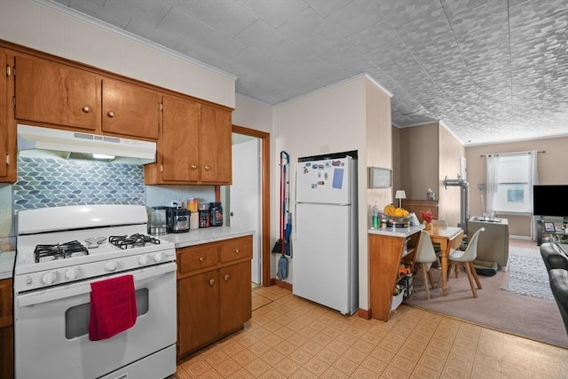 kitchen featuring under cabinet range hood, brown cabinets, white appliances, and light countertops