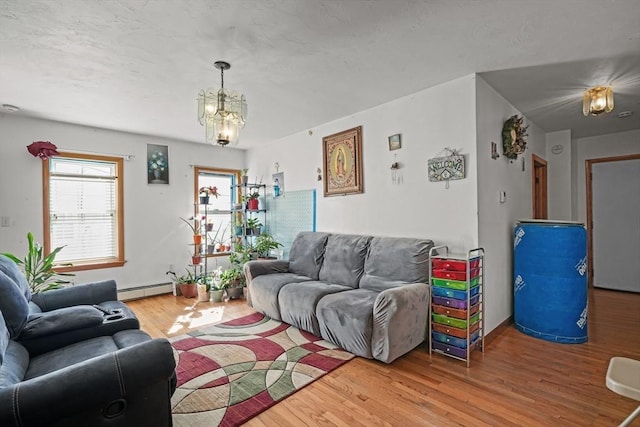 living area with an inviting chandelier, wood finished floors, and a baseboard radiator