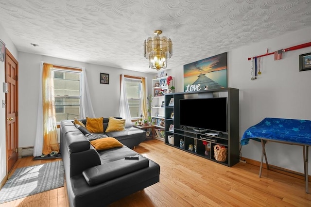 living room featuring baseboards, baseboard heating, light wood-style floors, a notable chandelier, and a textured ceiling