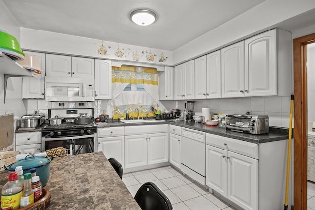 kitchen featuring white appliances, a toaster, a sink, white cabinets, and tasteful backsplash