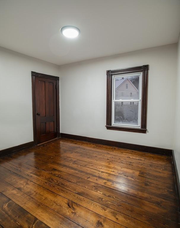 unfurnished room featuring dark wood-type flooring and baseboards