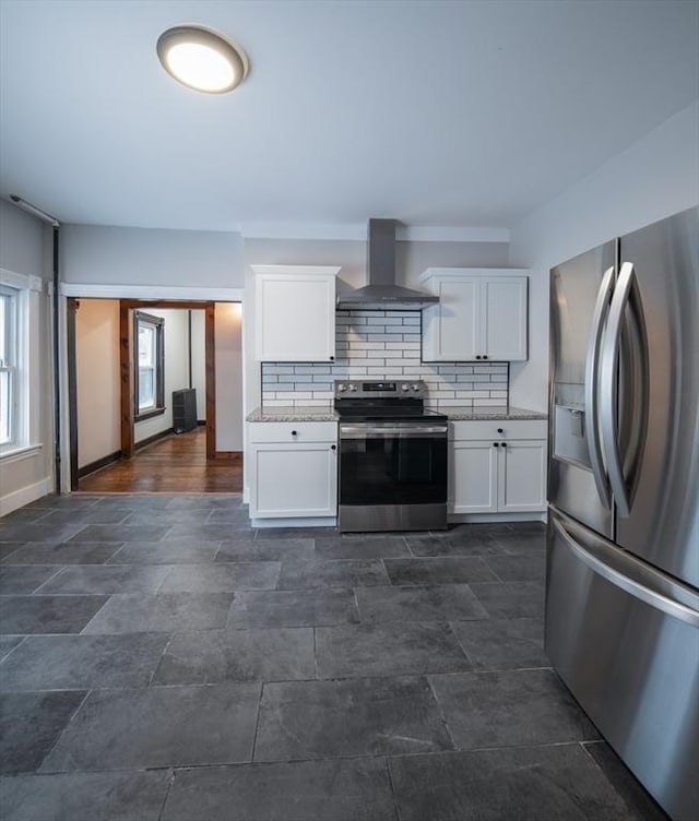 kitchen featuring stainless steel appliances, white cabinetry, wall chimney exhaust hood, and tasteful backsplash