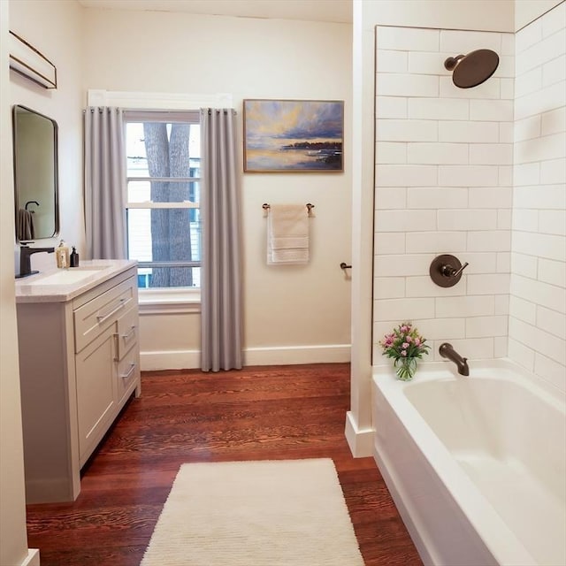 bathroom with baseboards, shower / washtub combination, wood finished floors, and vanity