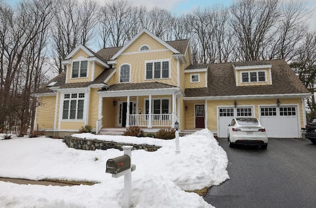 view of front of home with a porch, roof with shingles, a garage, and aphalt driveway