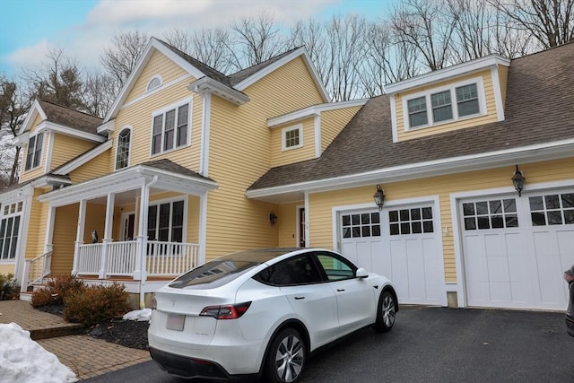 view of front of house with covered porch, aphalt driveway, and roof with shingles