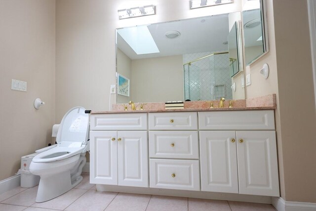 bathroom with toilet, a skylight, a shower stall, tile patterned floors, and double vanity