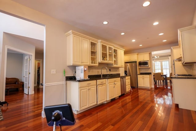 kitchen featuring dark wood-style flooring, stainless steel appliances, recessed lighting, glass insert cabinets, and a sink