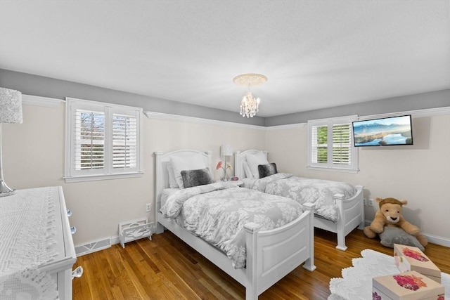bedroom featuring baseboards, an inviting chandelier, and wood finished floors