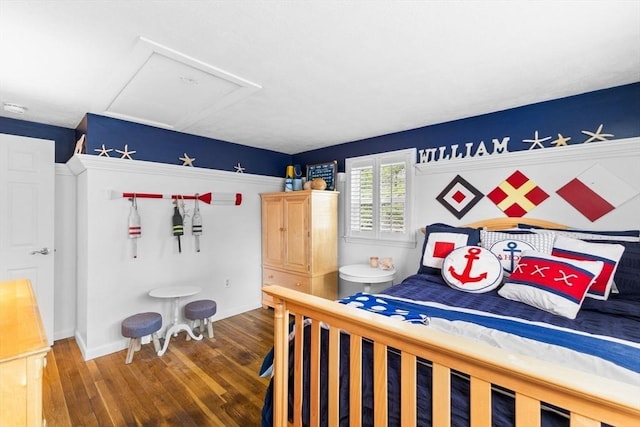 unfurnished bedroom with baseboards, attic access, and wood finished floors