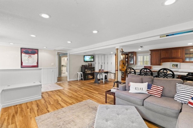 living area featuring light wood-style flooring, recessed lighting, and a wainscoted wall