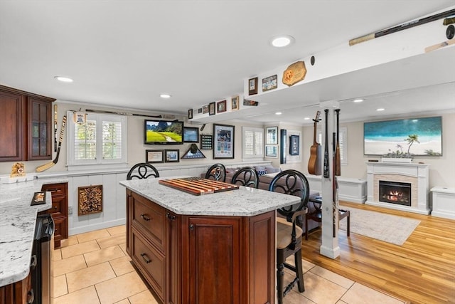 kitchen with open floor plan, glass insert cabinets, a kitchen island, and a breakfast bar area