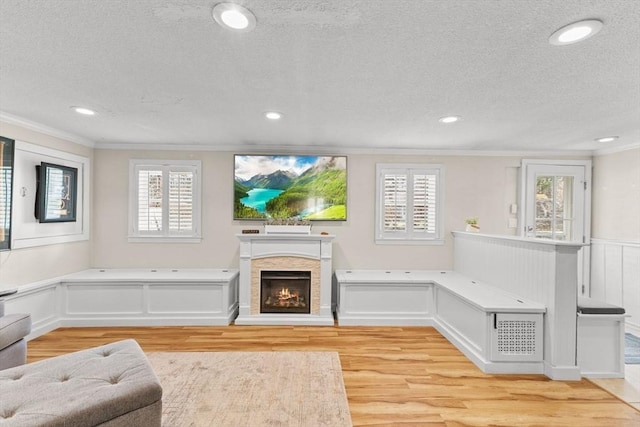 living room featuring light wood finished floors, crown molding, and a healthy amount of sunlight