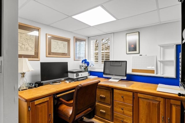 office space with a paneled ceiling and built in study area