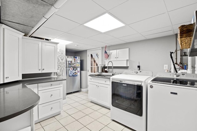 clothes washing area with cabinet space, light tile patterned floors, washing machine and clothes dryer, and a sink