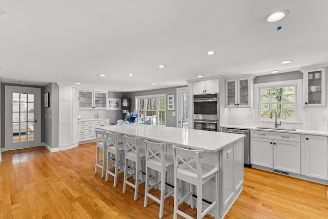 kitchen featuring a sink, light countertops, light wood-style floors, and stainless steel appliances